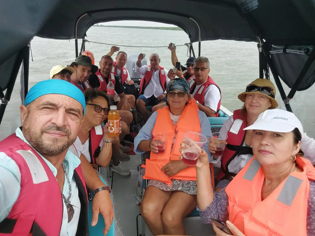 Grup de turiști veseli cu veste de salvare pe barca Corsar 700 în Delta Dunării